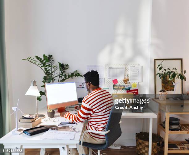 male entrepreneur using computer at home office - hybrid learning stock pictures, royalty-free photos & images