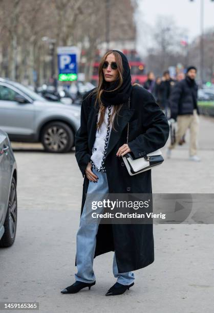 Chloe Harrouche wears black balaklava, denim jeans, black white two tone bag, black coat, sunglasses outside Chanel during Paris Fashion Week - Haute...