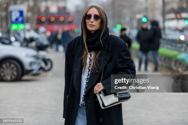 Chloe Harrouche wears black balaklava, denim jeans, black white two tone bag, black coat, sunglasses outside Chanel during Paris Fashion Week - Haute...
