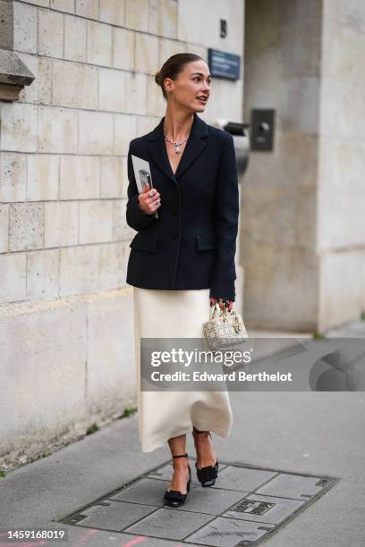 Guest wears a silver and diamonds pendant necklace, a black blazer jacket, a white latte matte midi skirt, a white pearls quilted pattern Lady...