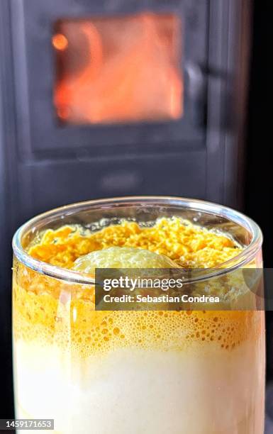 hot turmeric latte. served in white cup. ingredients partially in field of view are nutmeg, sugar, coconut milk, salt, ginger and turmeric. wooden plank. high point of view - good cholesterol stock pictures, royalty-free photos & images