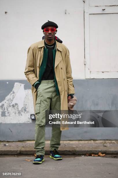 Guest wears a black felt / wool beret, red sunglasses, multicolored pearls necklaces, a white pearls necklace, a black t-shirt, a dark green teddy...