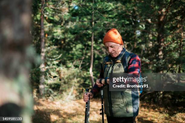 senior male hiker using smart watch to track his location in forest - old person with walking stick outside standing stock pictures, royalty-free photos & images