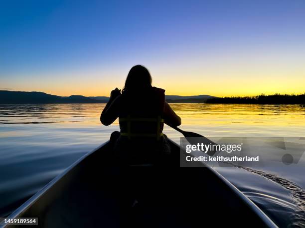 rear view silhouette of a woman canoeing in patricia bay at sunset, north saanich near sidney, british columbia, canada - rowboat stock pictures, royalty-free photos & images