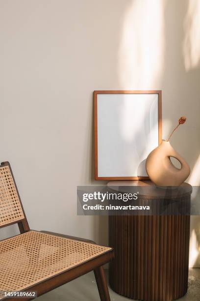 blank wooden picture frame and modern vase on a side table next to a chair - tavolino di servizio foto e immagini stock