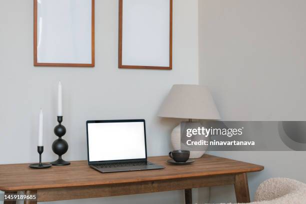 open laptop with a blank screen, candlesticks and a lamp on a table below two empty picture frames - candle holder stock pictures, royalty-free photos & images