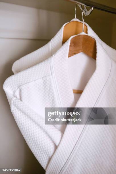 close-up of two white dressing gowns hanging in a wardrobe - bathrobe stock pictures, royalty-free photos & images