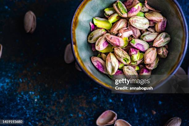 overhead view of a bowl of shelled pistachio nuts - nature morte photos et images de collection