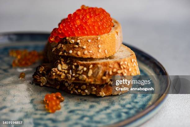 slices of seeded sourdough bread with red caviar on a ceramic plate - red caviar stock pictures, royalty-free photos & images