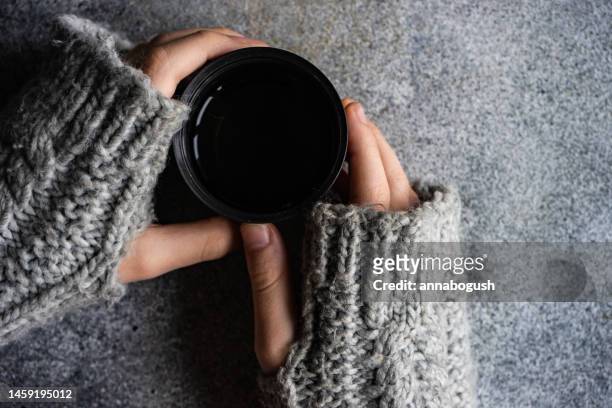 overhead view of a person wearing fingerless gloves holding a warm drink - fingerless gloves stock-fotos und bilder