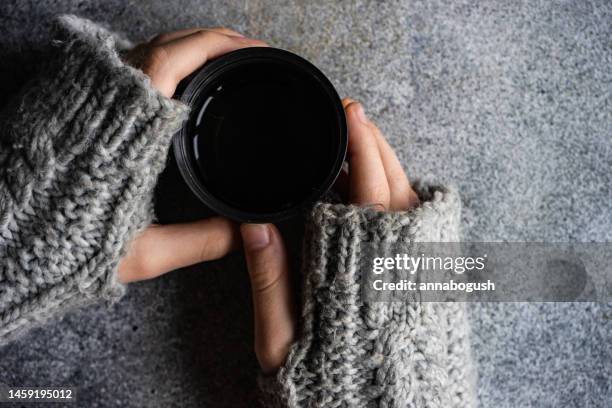 overhead view of a person wearing fingerless gloves holding a warm drink - fingerless glove stockfoto's en -beelden