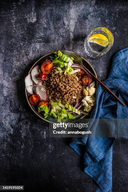 overhead view of a buckwheat, cabbage, tomato, radish, red onion and cauliflower salad with a glass of lemon water - fagópiro - fotografias e filmes do acervo