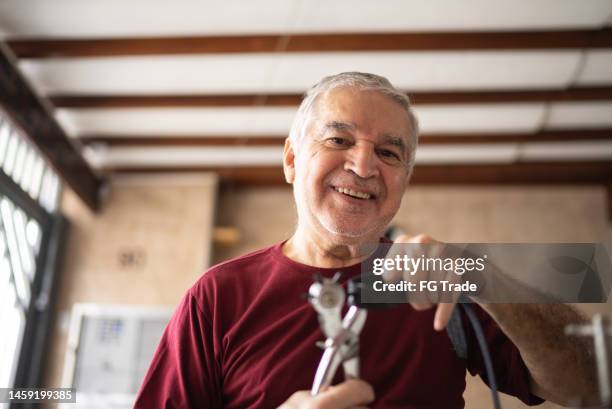 portrait d’un homme âgé utilisant un poinçon en cuir sur une ceinture à la maison - maroquinerie photos et images de collection