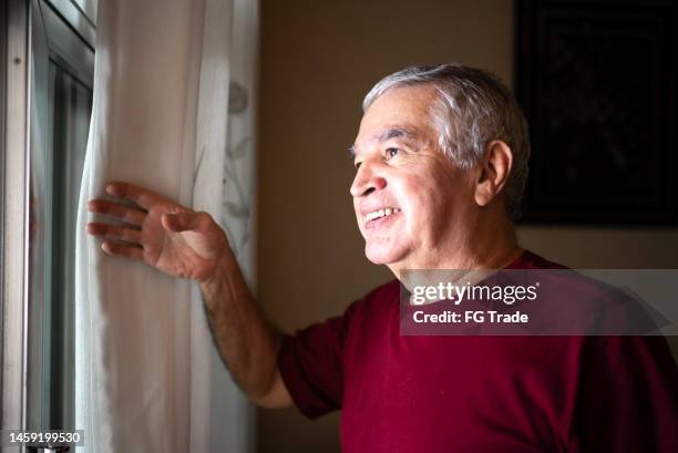 senior man contemplation while looking through the window at home - udd thailand stock pictures, royalty-free photos & images