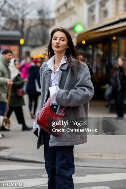 Guest wears grey jacket, white button shirt, dark blue denim jeans, red bag outside Alexis Mabille during Paris Fashion Week - Haute Couture Spring...