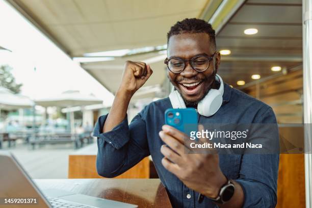 happy young african-american man got a good news - excitement phone stock pictures, royalty-free photos & images