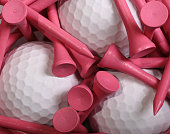 Wooden pink golf tees around three white golf balls 