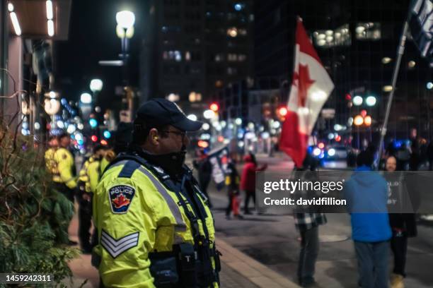 line of police officers guarding building while protestors are out front. - canada government stock pictures, royalty-free photos & images