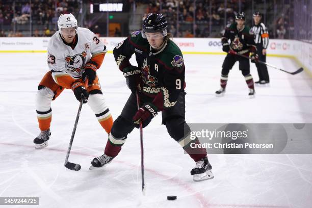 Clayton Keller of the Arizona Coyotes skates with the puck ahead of Jakob Silfverberg of the Anaheim Ducks during the second period of the NHL game...