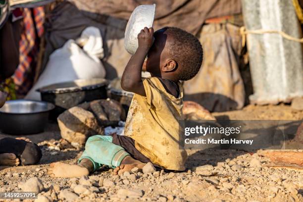 close-up.malnourished child due to extreme poverty, drought and climate change. eating and drinking maize porridge in front of his dwelling. kenya - fome extrema - fotografias e filmes do acervo