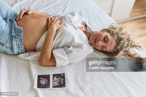 mujer embarazada que enaltece su vientre - mes fotografías e imágenes de stock