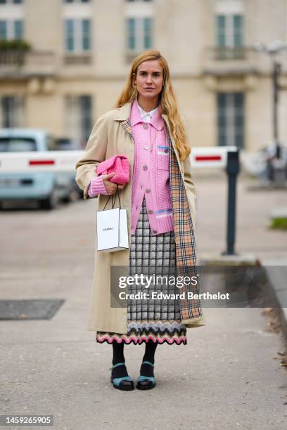 Blanca Miro wears a white shirt, a pale pink braided wool buttoned cardigan from Chanel, a beige long trench coat, a black and white checkered print...