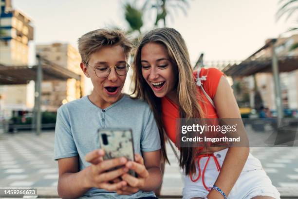 des adolescents consultent les médias sociaux sur la promenade de la plage d’alicante, en espagne - girl laughing photos et images de collection