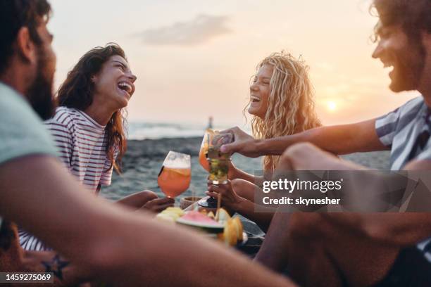 fröhliche freunde genießen obst und getränke am strand bei sonnenuntergang. - cocktail sonnenuntergang stock-fotos und bilder