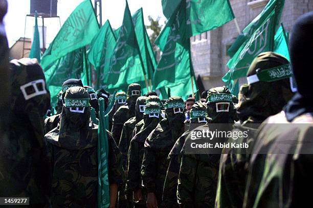 Masked members of the Islamic militant Hamas group hold Islamic flags during a march in the Jabalya refugee camp to protest against the U.S. Position...