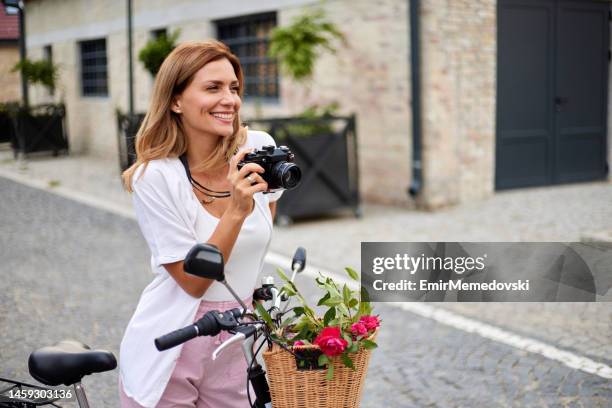 junge frau mit fahrradkamera und fotos im freien - bike flowers stock-fotos und bilder