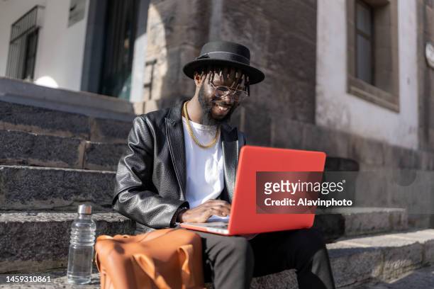 man on the street using a laptop computer laughing - street photography stock pictures, royalty-free photos & images