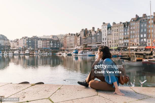 full length view of traveler woman with backpack sightseeing at honfleur harbour canal in france - calvados foto e immagini stock
