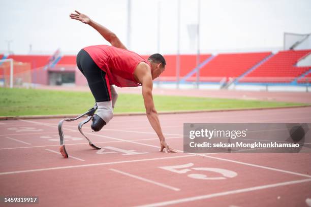 athlete with prosthetic leg in starting position at running track. - estadio de atletismo fotografías e imágenes de stock