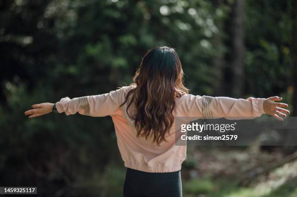 real view portrait of young asian woman breathing fresh air outdoors in rainforest - fresh air breathing stockfoto's en -beelden