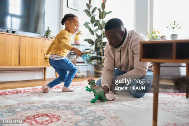 uomo africano che gioca con il figlio sorridente a casa - famiglia a casa foto e immagini stock