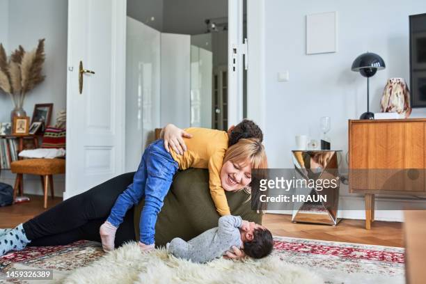 loving mother playing with her sons on living room floor - family at home stock pictures, royalty-free photos & images