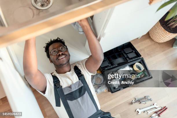 plumber working on pipes under sink - plumber stock pictures, royalty-free photos & images