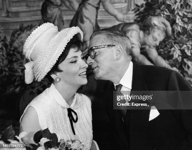 Sir Laurence Olivier kisses Italian actress Gina Lollobrigida at the Italian embassy in Grosvenor Square, London, after she presented him with...