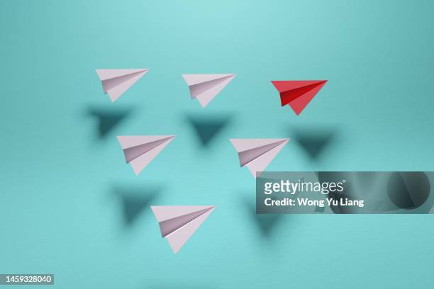 red paper plane  in group of white , 3d render - paper plane stock-fotos und bilder