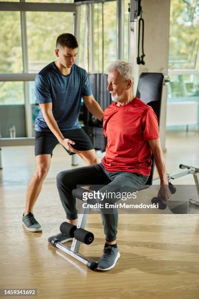 senior mann trainieren mit personal trainer mit hanteln im fitnessstudio - arbeiten pflege senior stock-fotos und bilder