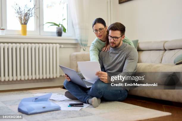 couple sitting in their living room and checking their finances using laptop - demonstration against the marriage for all bill stock pictures, royalty-free photos & images