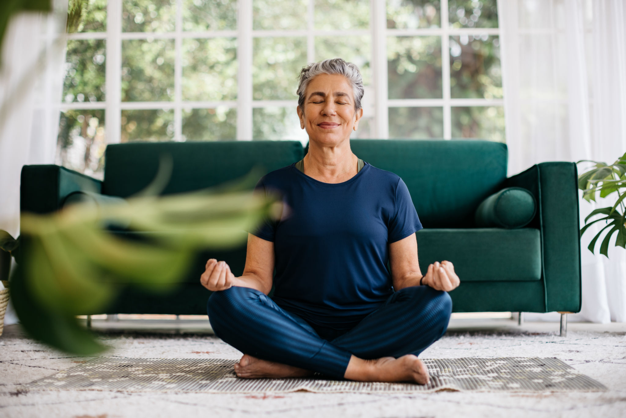 Relajar la mente y encontrar la paz interior con el yoga: Mujer mayor meditando en casa Relajar la mente y encontrar la paz interior con el yoga: Mujer mayor meditando en casa