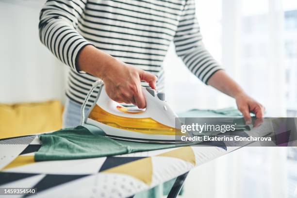 close-up of women's hands with an iron with steam - iron fotografías e imágenes de stock