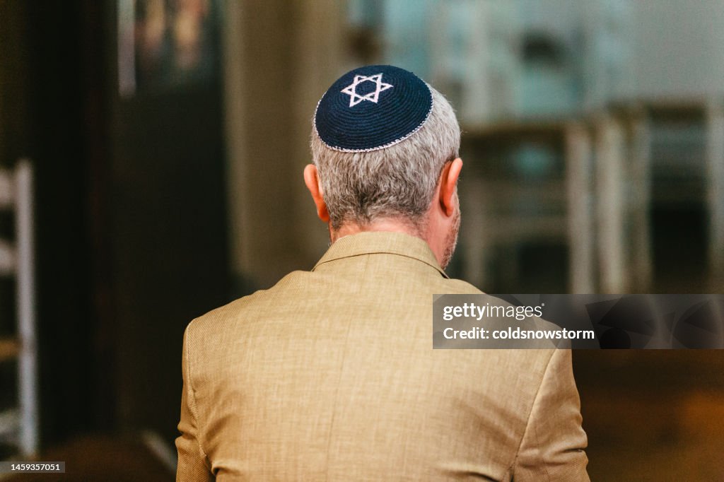 Jewish man wearing yarmulke praying in synagogue
