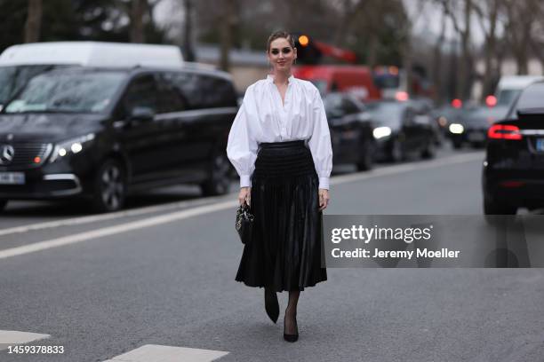 Chiara Ferragni seen wearing a Dior look with a white oversized blouse, black heels, a black pleated skirt and a matching black leather bag by Dior...