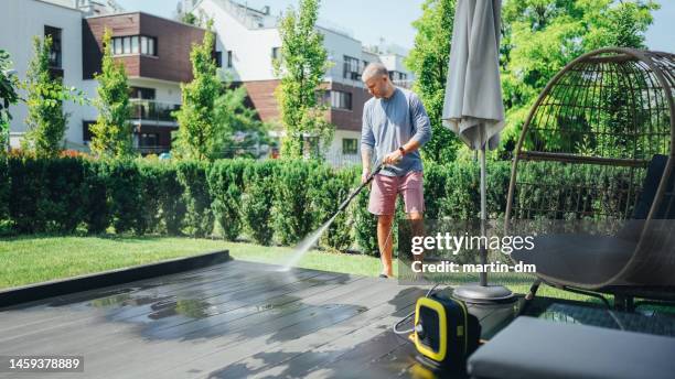 hombre limpiando su terraza con lavadora de alta presión - garden decking fotografías e imágenes de stock