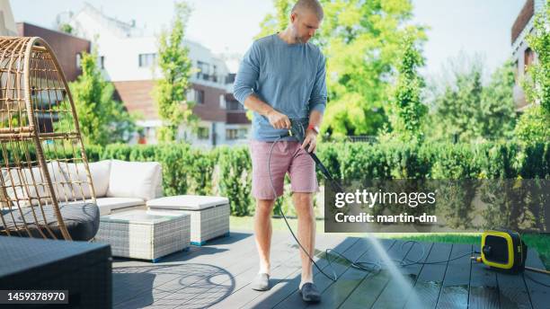 homem limpando sua varanda com arruela de alta pressão - high pressure cleaning - fotografias e filmes do acervo