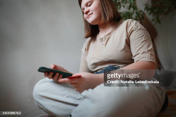 overweight teenage girl pays for purchase on internet by credit card. copy space. - plump girls stock pictures, royalty-free photos & images