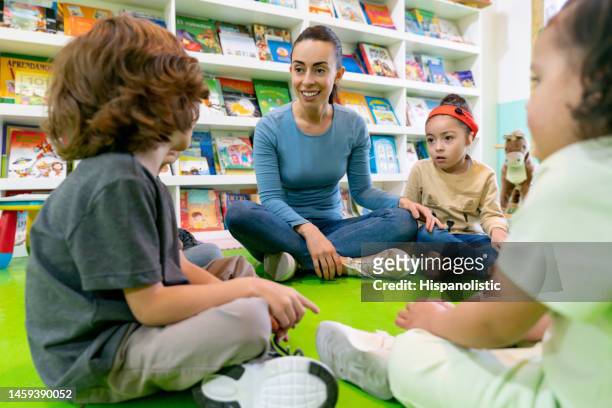 teacher listening to a group of children telling stories at the school - special education stock pictures, royalty-free photos & images