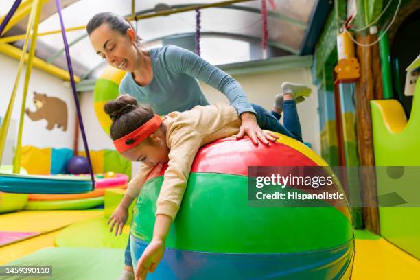 teacher helping a girl with hearing aid while playing in the playground - assistive technology student stock pictures, royalty-free photos & images